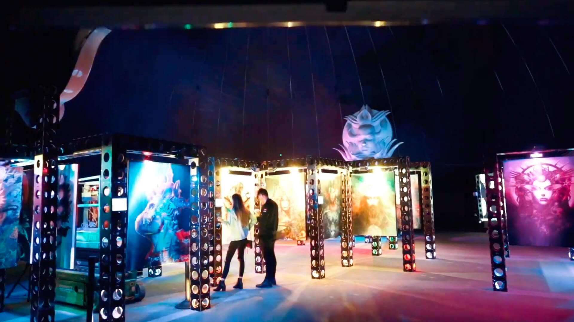 Visitors walk through a brightly lit exhibition of large illuminated panels.