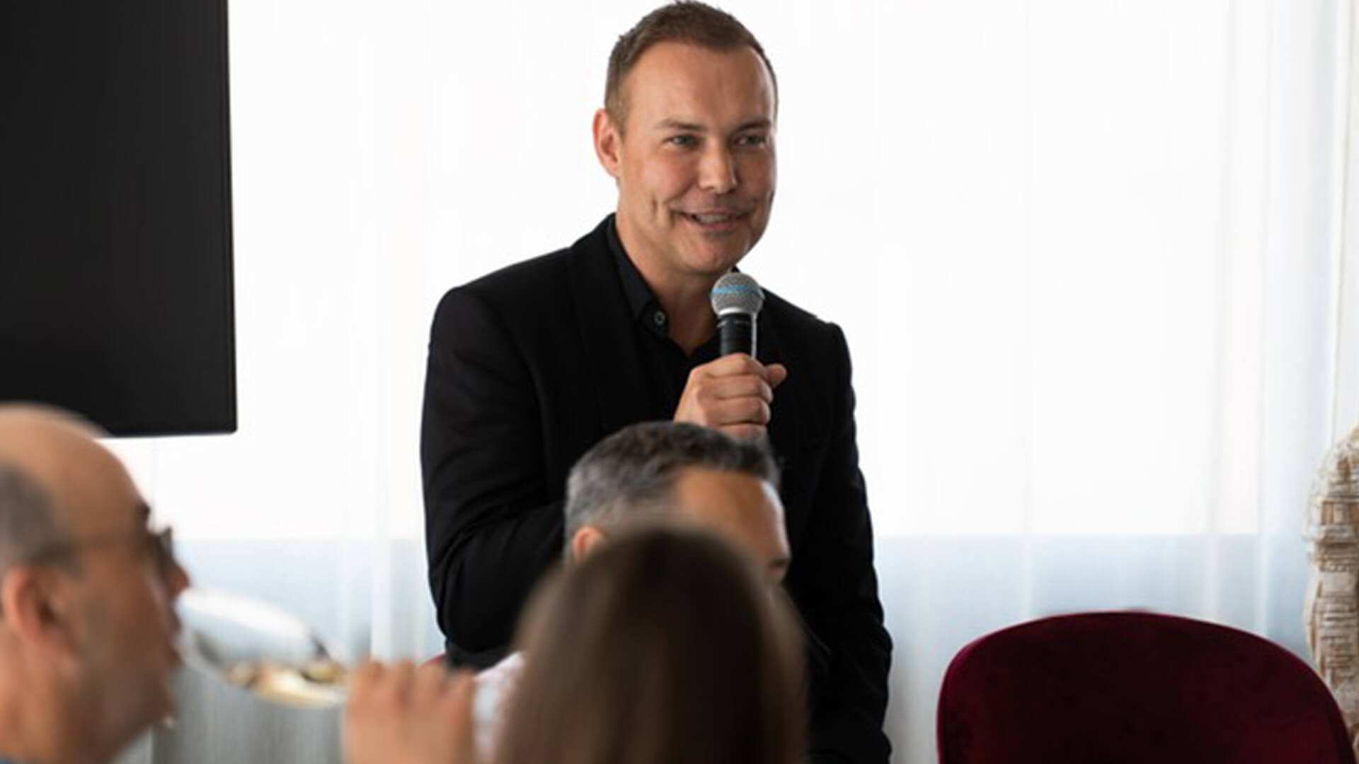 A man speaks into a microphone to a seated audience.