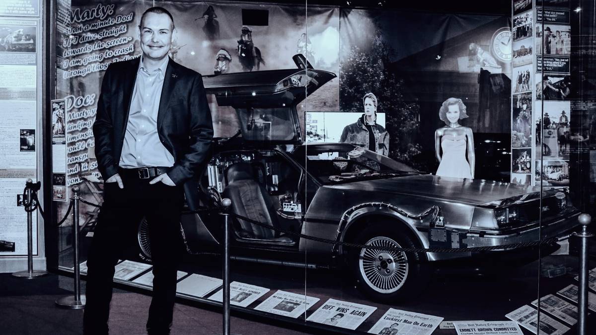 Francis Hellyer stands beside the DeLorean from Back to the Future, in its display at The Hollywood Museum.